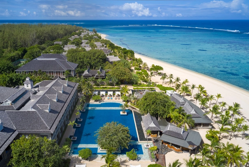 Panorámica aérea de The St. Regis Le Morne Resort con piscinas, jardines tropicales y una extensa playa de arena blanca.