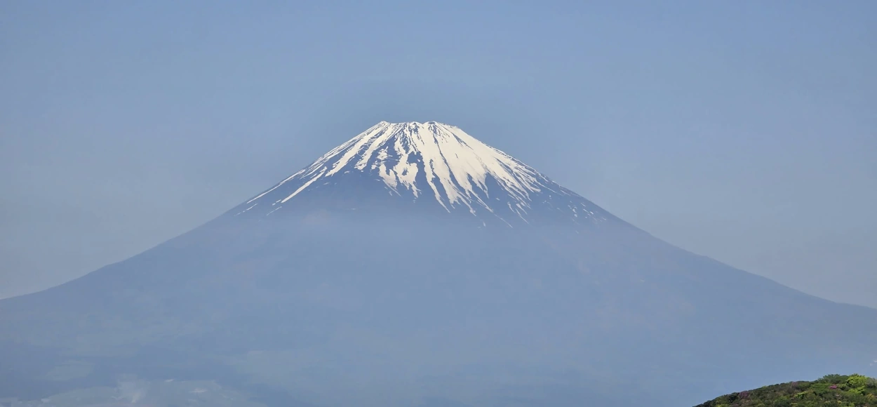 Monte Fuji con la cumbre nevada elevándose sobre el paisaje de Japón bajo un cielo despejado.