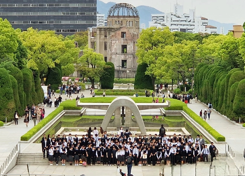 Grupo de estudiantes junto al cenotafio del Parque de la Paz de Hiroshima, con la Cúpula de la Bomba Atómica al fondo.